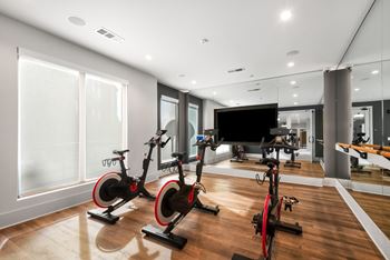 Three exercise bikes are lined up in a spacious room.